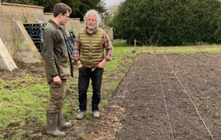 Pete Richardson and Dom looking at organic vegetables in a freshly cultivated field