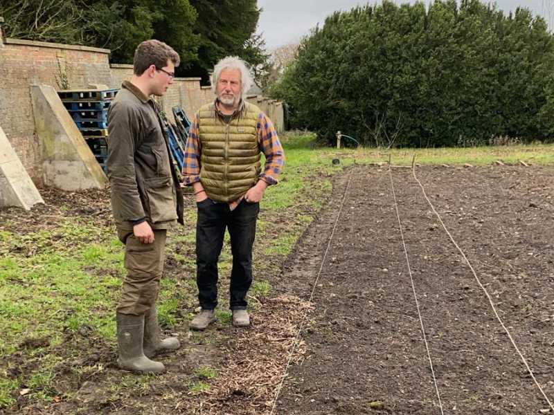 Pete Richardson and Dom looking at organic vegetables in a freshly cultivated field