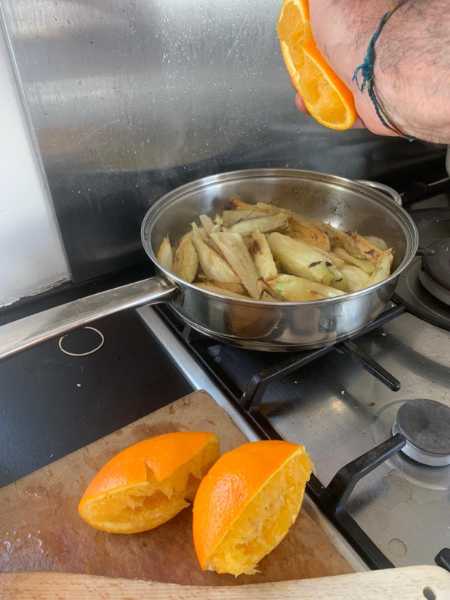 Squeezing fresh orange juice into a pan of fennel